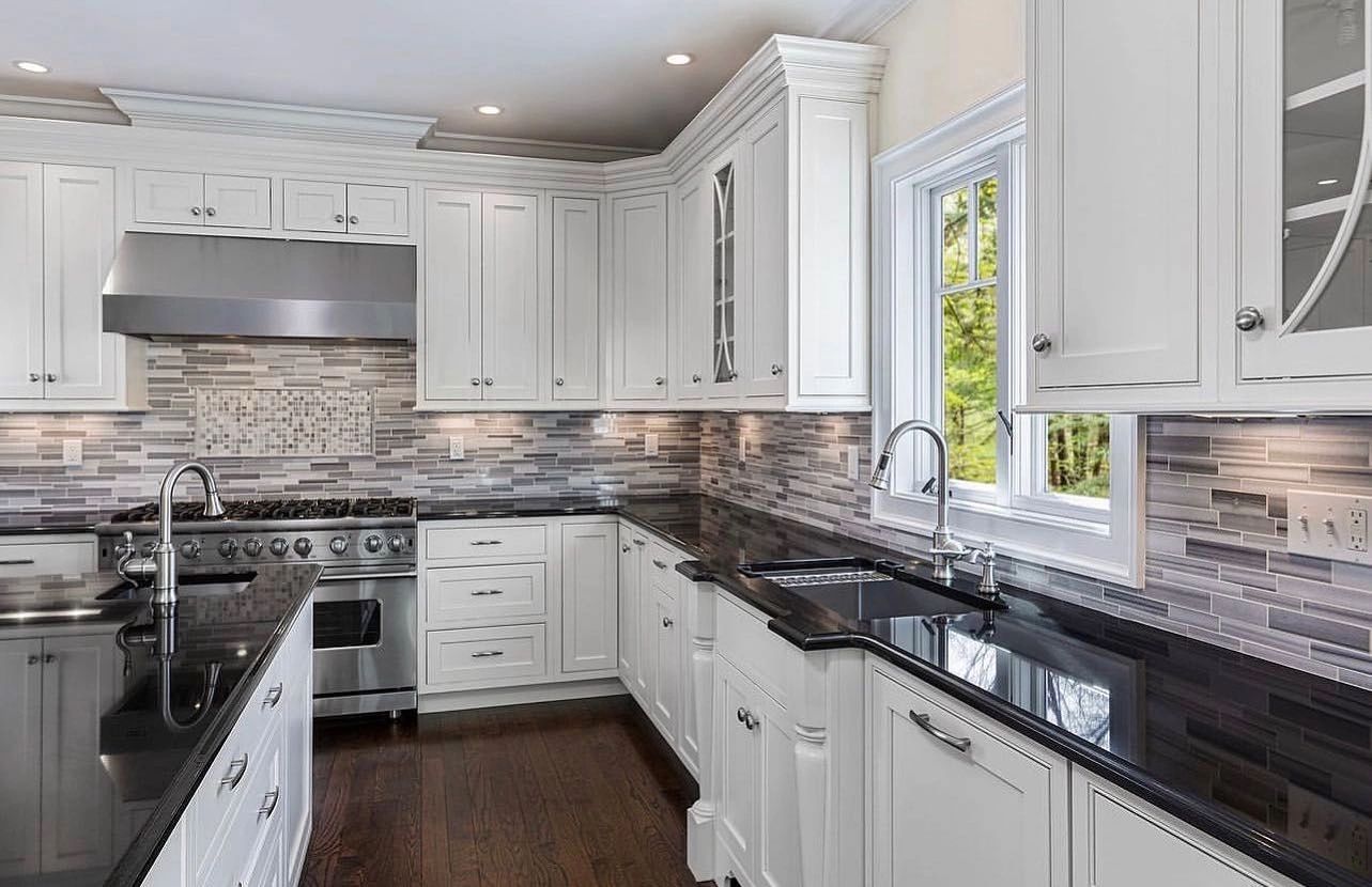 Rift-oak slab kitchen with black-and-gold granite island and gold chandeliers by Green Tech