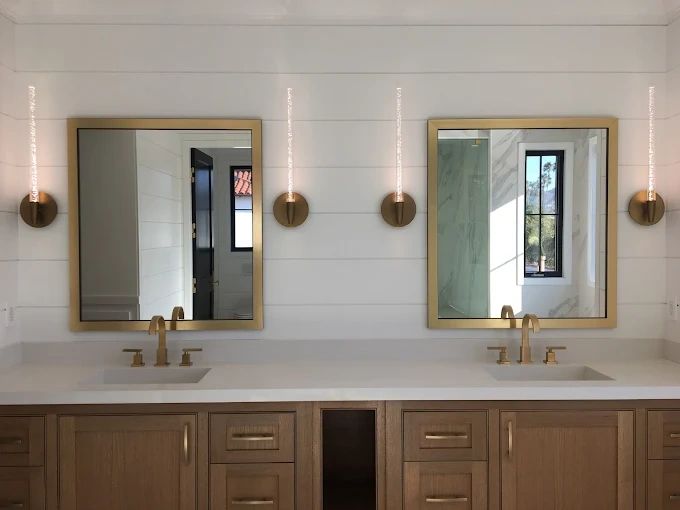 Green Tech bathroom remodel — luxury vanity with brass faucets and gold-framed mirrors