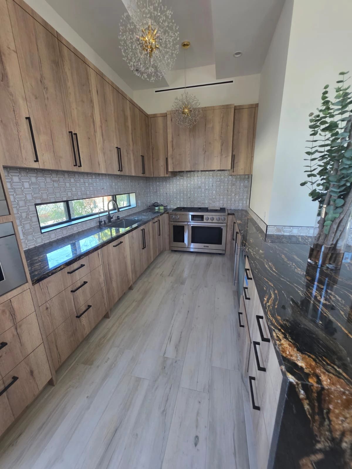 Galley-style kitchen with light wood cabinetry and stainless steel appliances